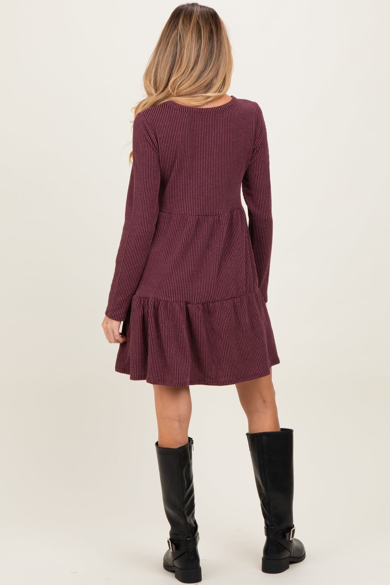 woman wearing a burgundy long sleeve maternity dress with a tiered hem and ribbed texture from the back