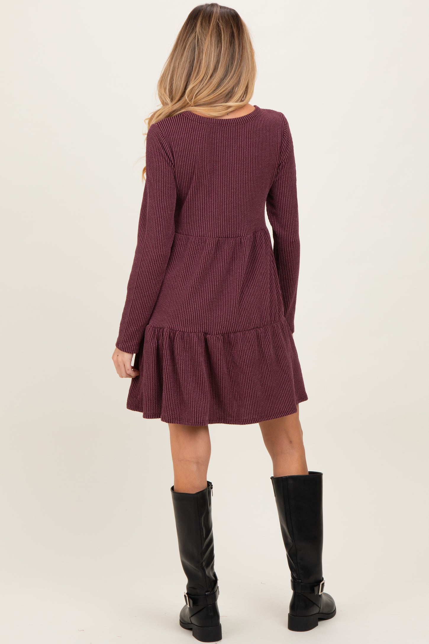woman wearing a burgundy long sleeve maternity dress with a tiered hem and ribbed texture from the back