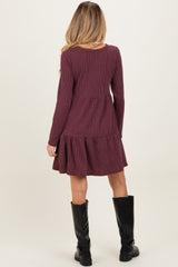 woman wearing a burgundy long sleeve maternity dress with a tiered hem and ribbed texture from the back