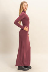 woman wearing a maroon long sleeve fitted maxi dress with a high neckline and a side silhouette