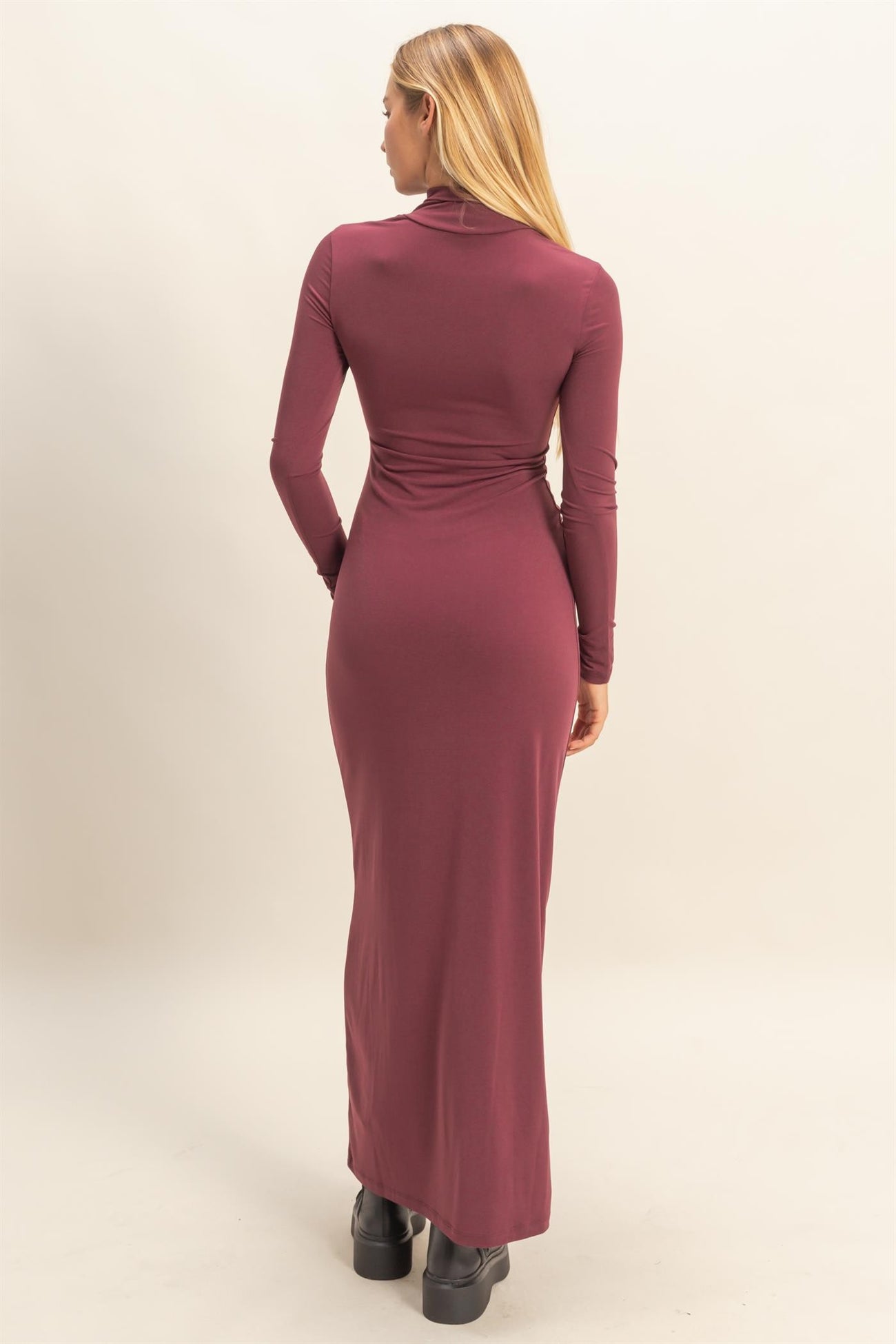 woman wearing a burgundy long sleeve bodycon maxi dress, showing the back view with a fitted silhouette