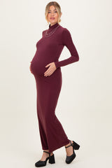woman wearing a burgundy long sleeve maternity dress with a high neckline, showcasing her baby bump