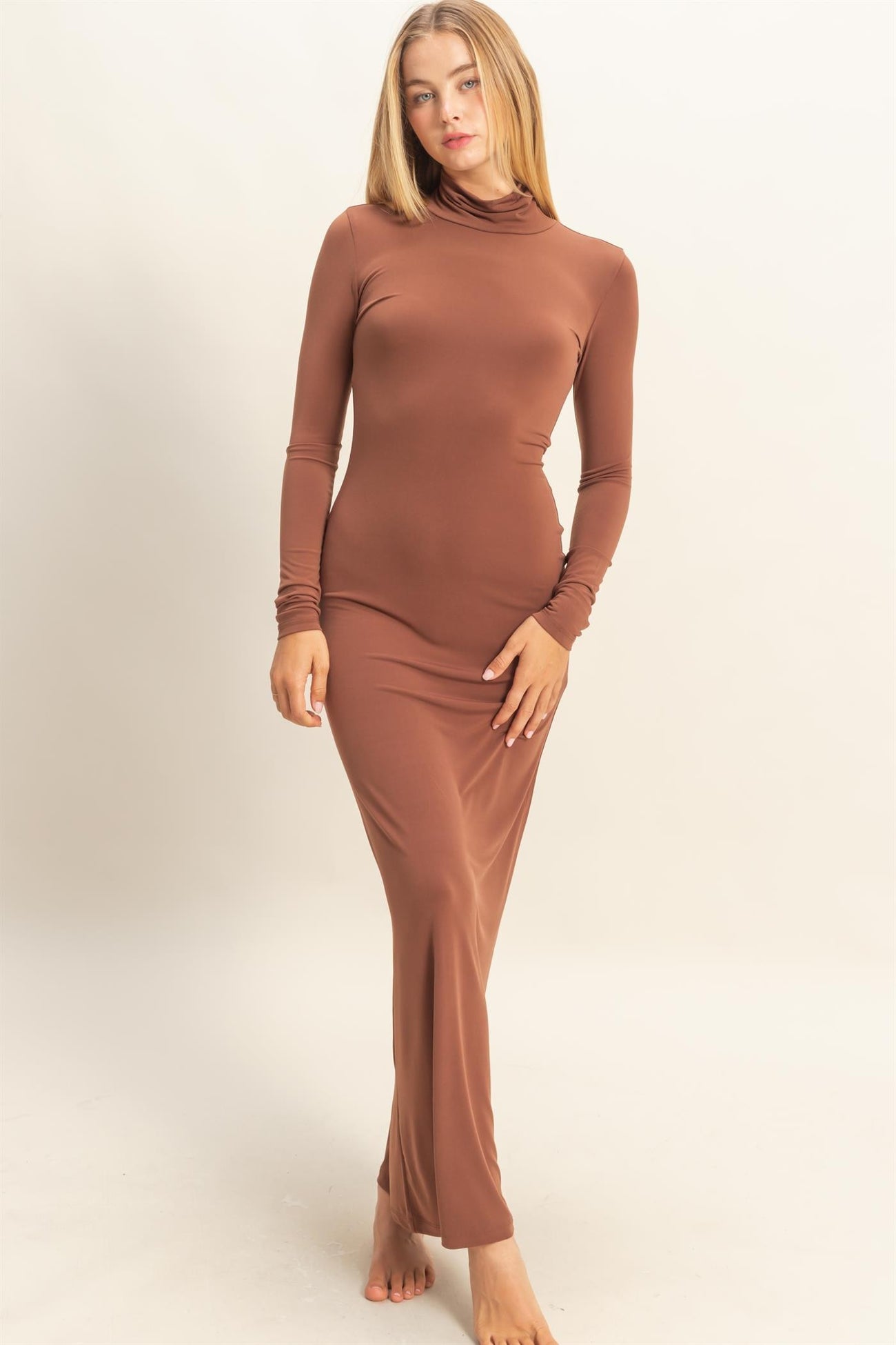 woman wearing a brown long sleeve maxi dress with a high neckline and fitted silhouette
