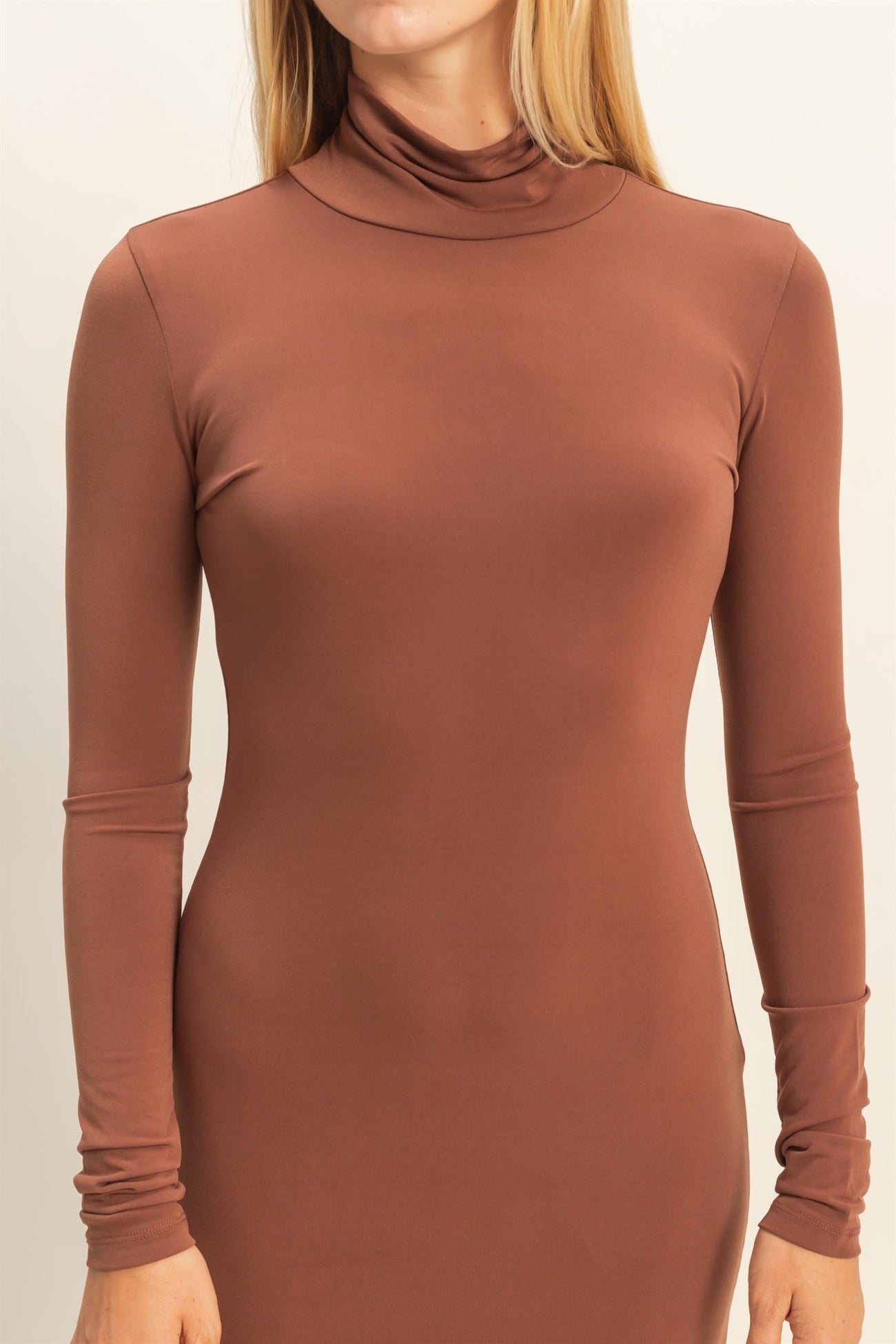woman wearing a brown long sleeve turtleneck dress with a fitted silhouette