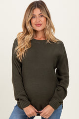 woman wearing an olive green textured maternity sweater with a visible baby bump
