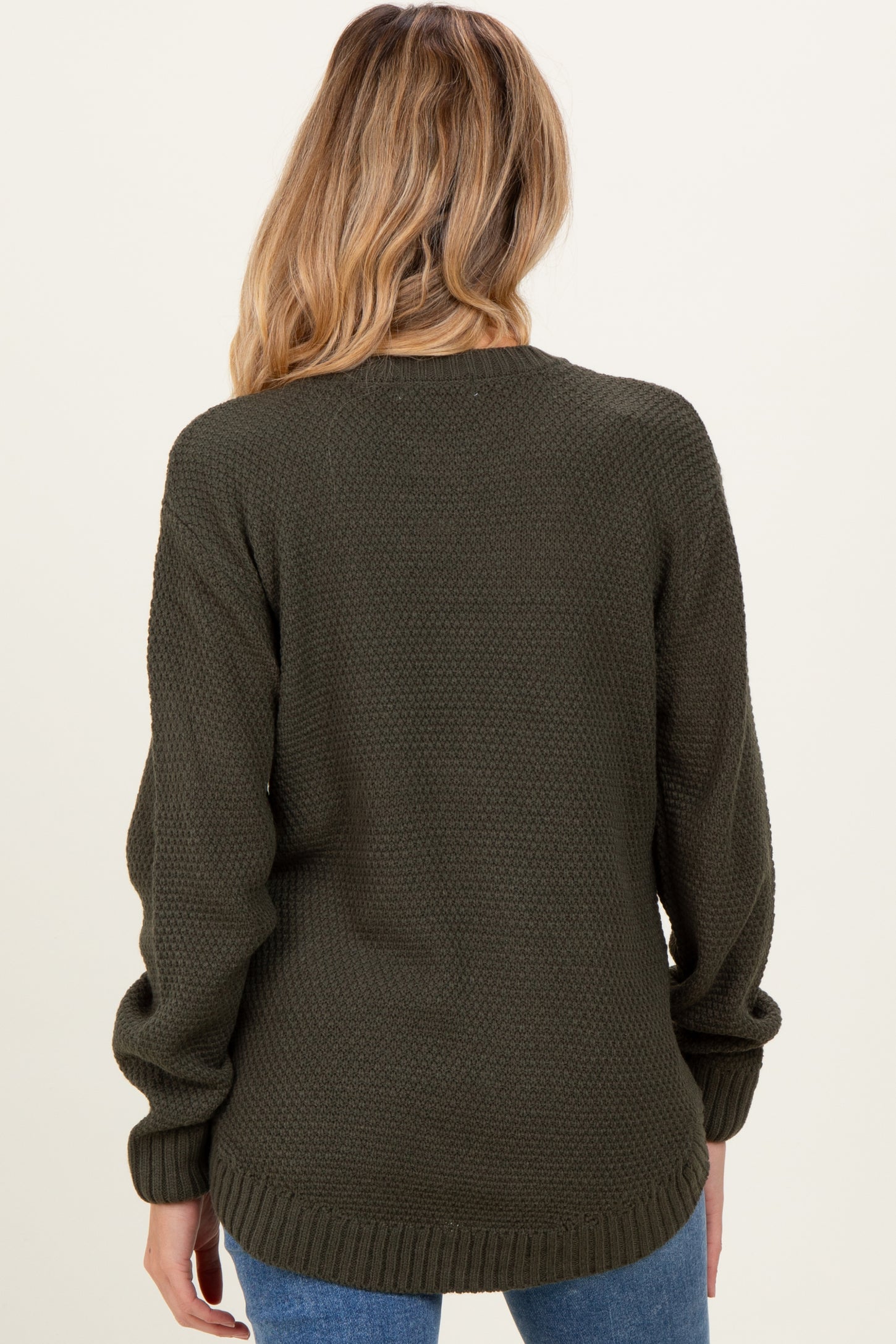 woman wearing a dark green maternity sweater with a textured pattern, showing the back view