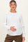 woman wearing a white lightweight maternity sweater and holding her baby bump
