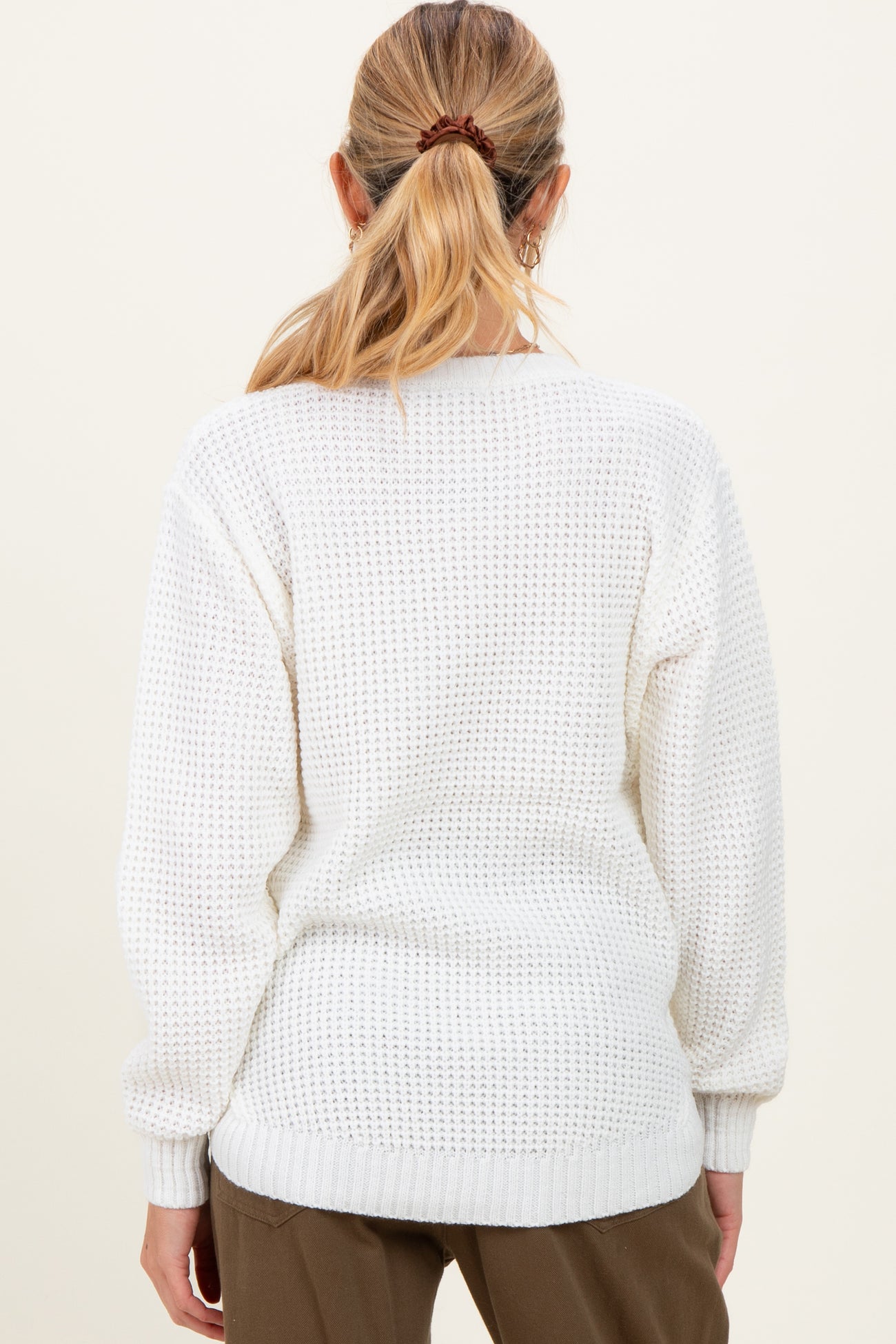 woman wearing a white knitted maternity sweater with dropped shoulders and a relaxed fit, showing the back view