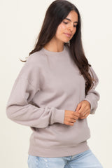 woman wearing a light taupe oversized sweatshirt with long sleeves and relaxed fit