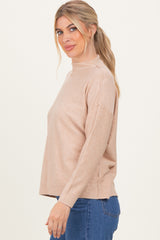 woman wearing a beige mock neck sweater with relaxed fit and long sleeves, paired with blue jeans