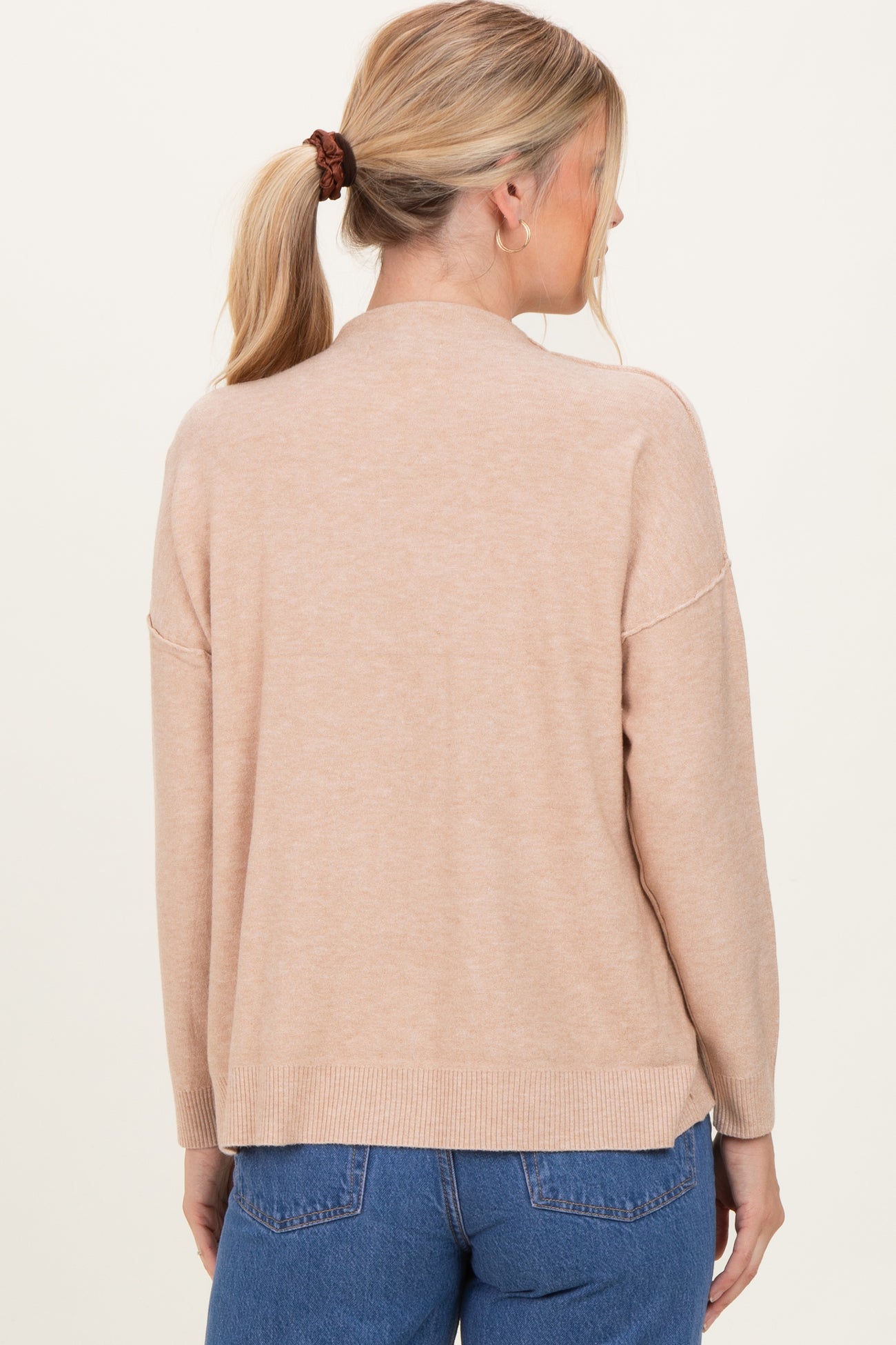 woman wearing a cozy beige long sleeve sweater with a relaxed fit and ribbed hem, shown from the back