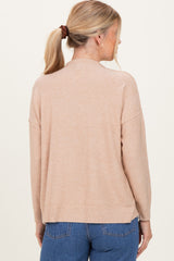 woman wearing a cozy beige long sleeve sweater with a relaxed fit and ribbed hem, shown from the back