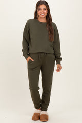 woman wearing a dark green maternity loungewear set with drawstring pants and long sleeve top, styled casually