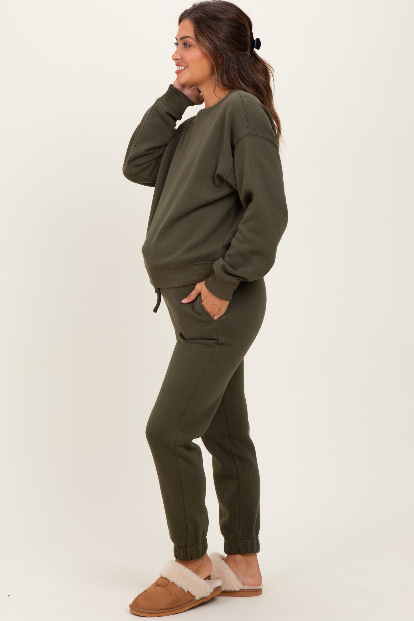 woman wearing an olive green maternity loungewear set with a relaxed fit sweatshirt and jogger pants, showing a baby bump
