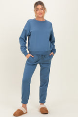 woman wearing a blue maternity sweatshirt and matching sweatpants with pockets and drawstring, styled casually