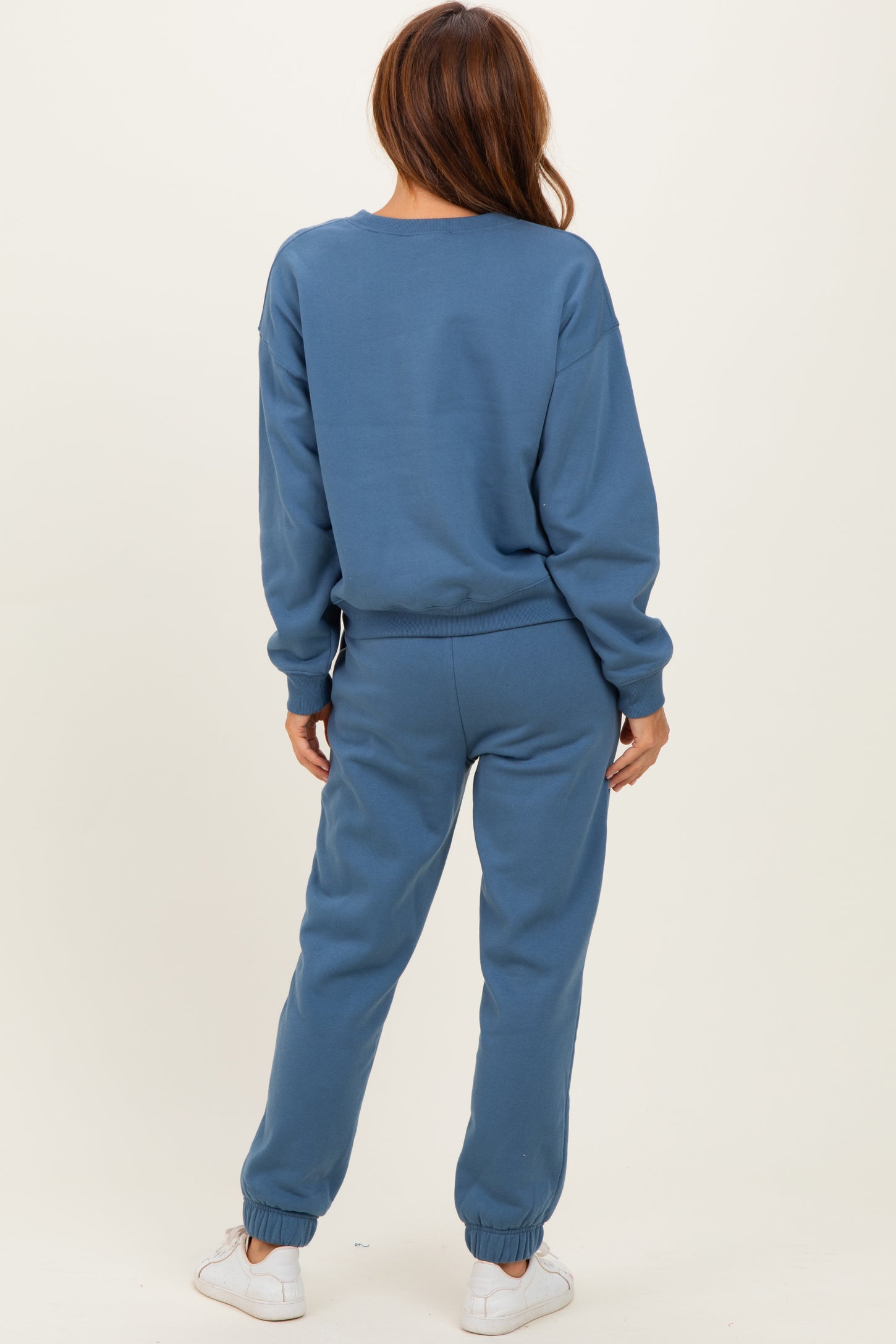 woman wearing a blue cozy sweatshirt and matching jogger pants, viewed from the back