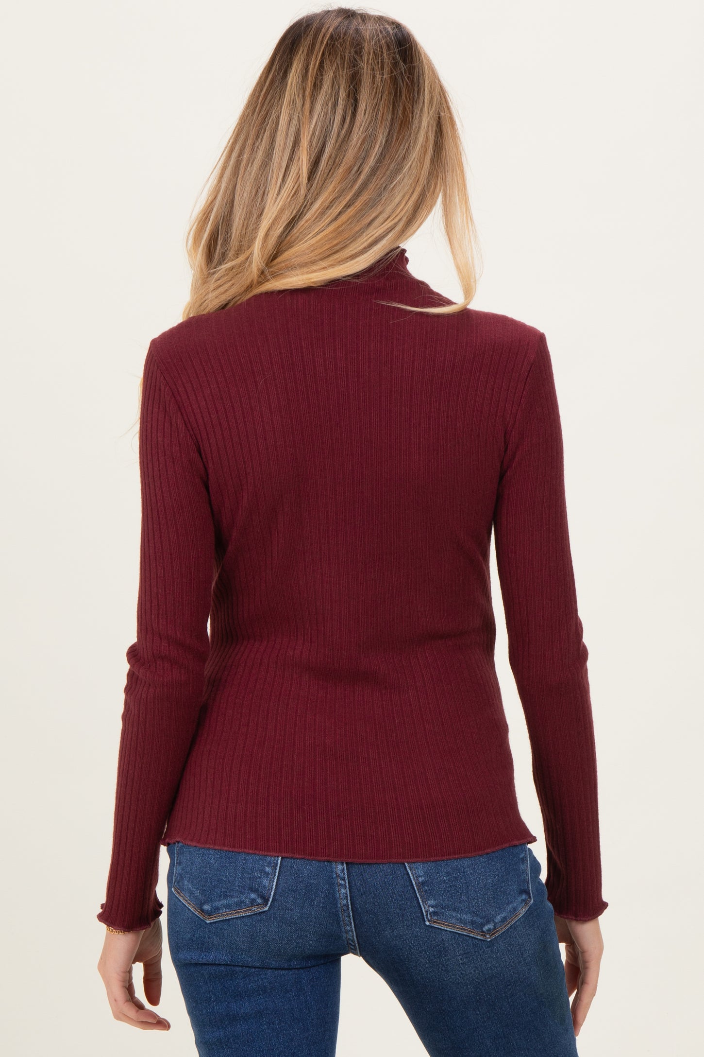 woman wearing a maroon ribbed long sleeve maternity top, shown from the back with fitted style details