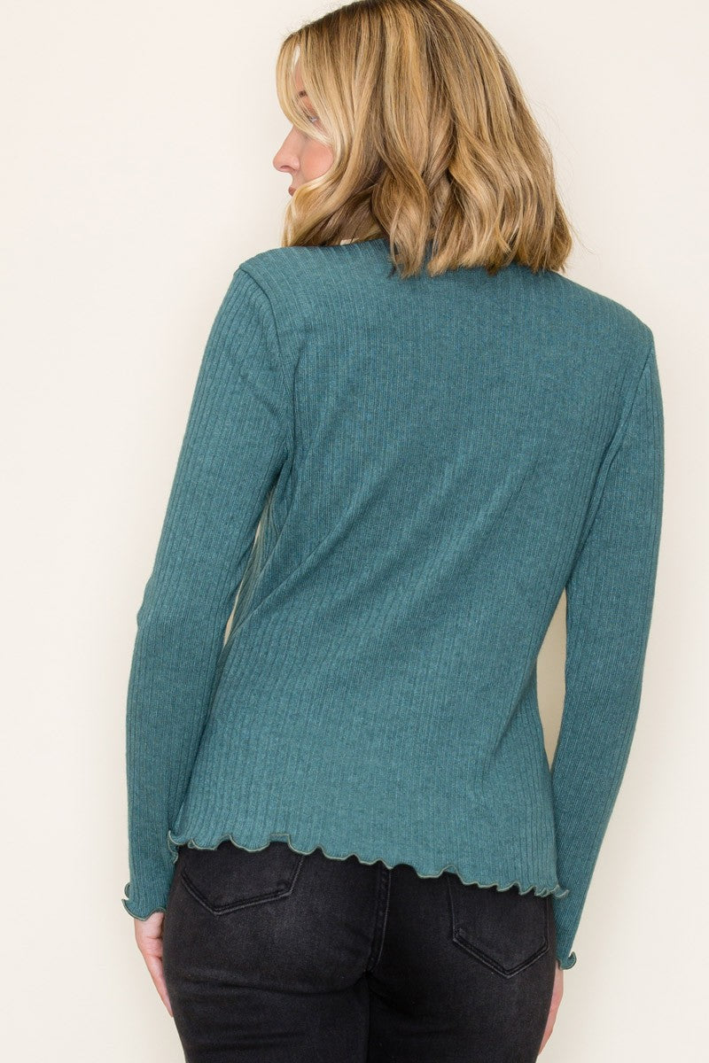 woman wearing a teal ribbed long sleeve top with scalloped hem, viewed from the back