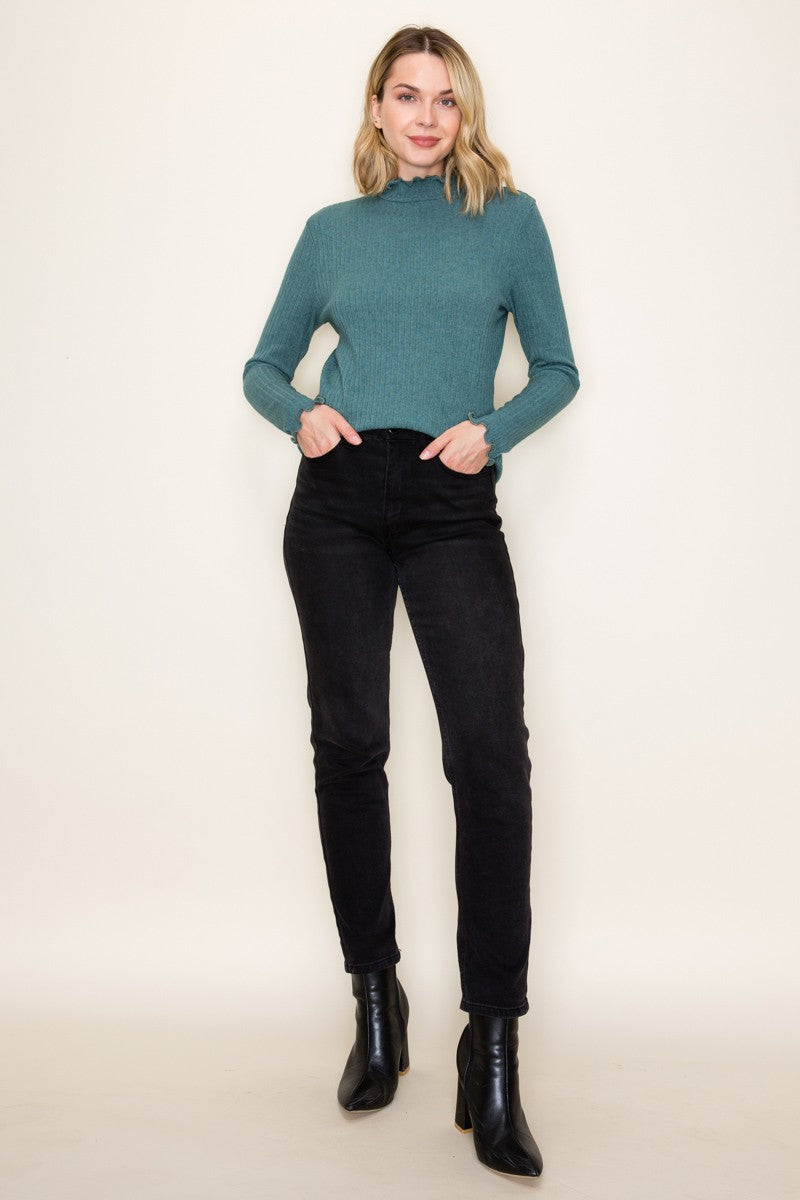 woman wearing a teal ribbed long sleeve sweater and black high-waisted jeans with ankle boots