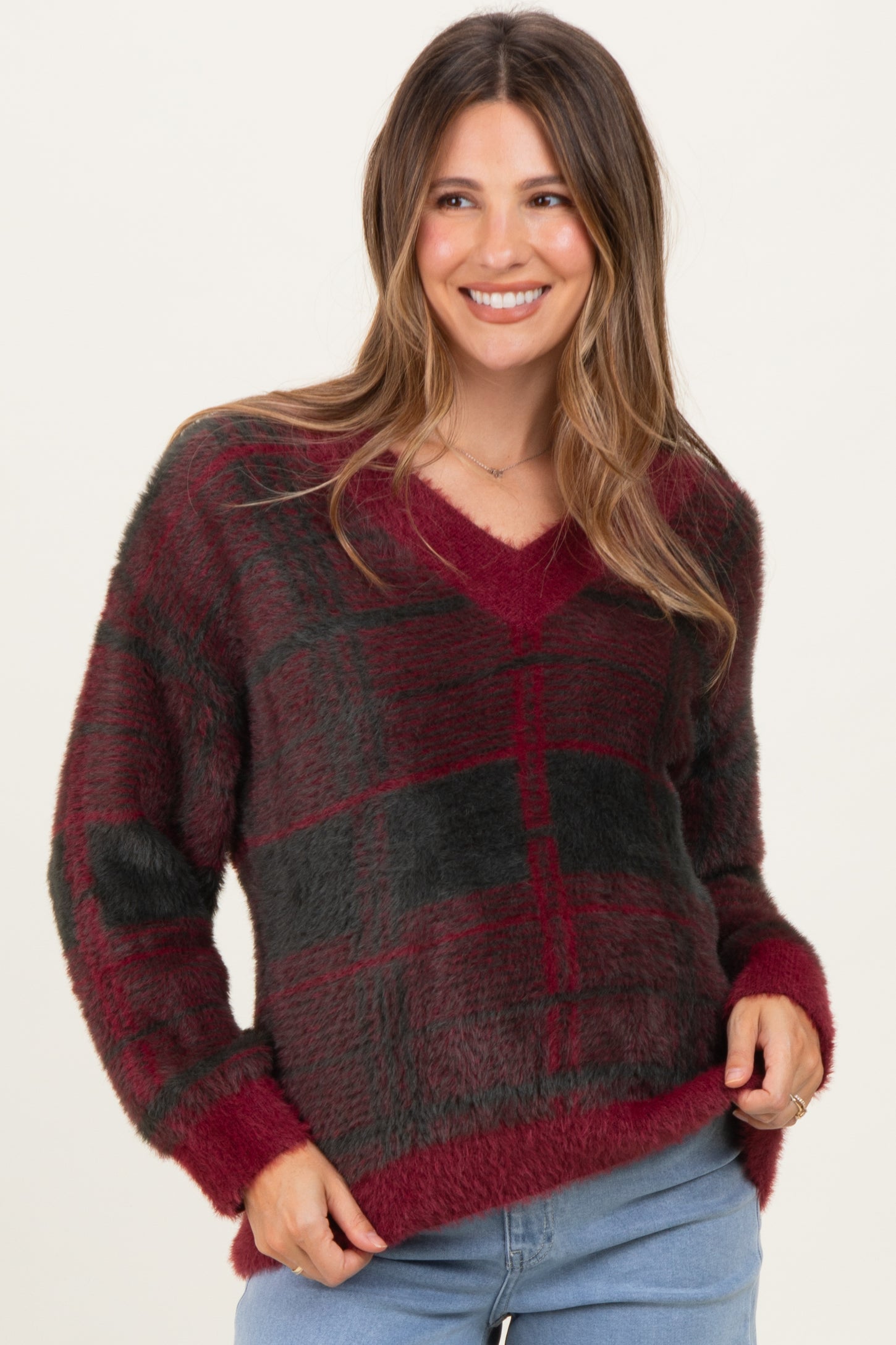 woman wearing a burgundy and black plaid v-neck maternity sweater with a relaxed fit and long sleeves