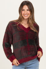 woman wearing a burgundy and black plaid v-neck maternity sweater with a relaxed fit and long sleeves