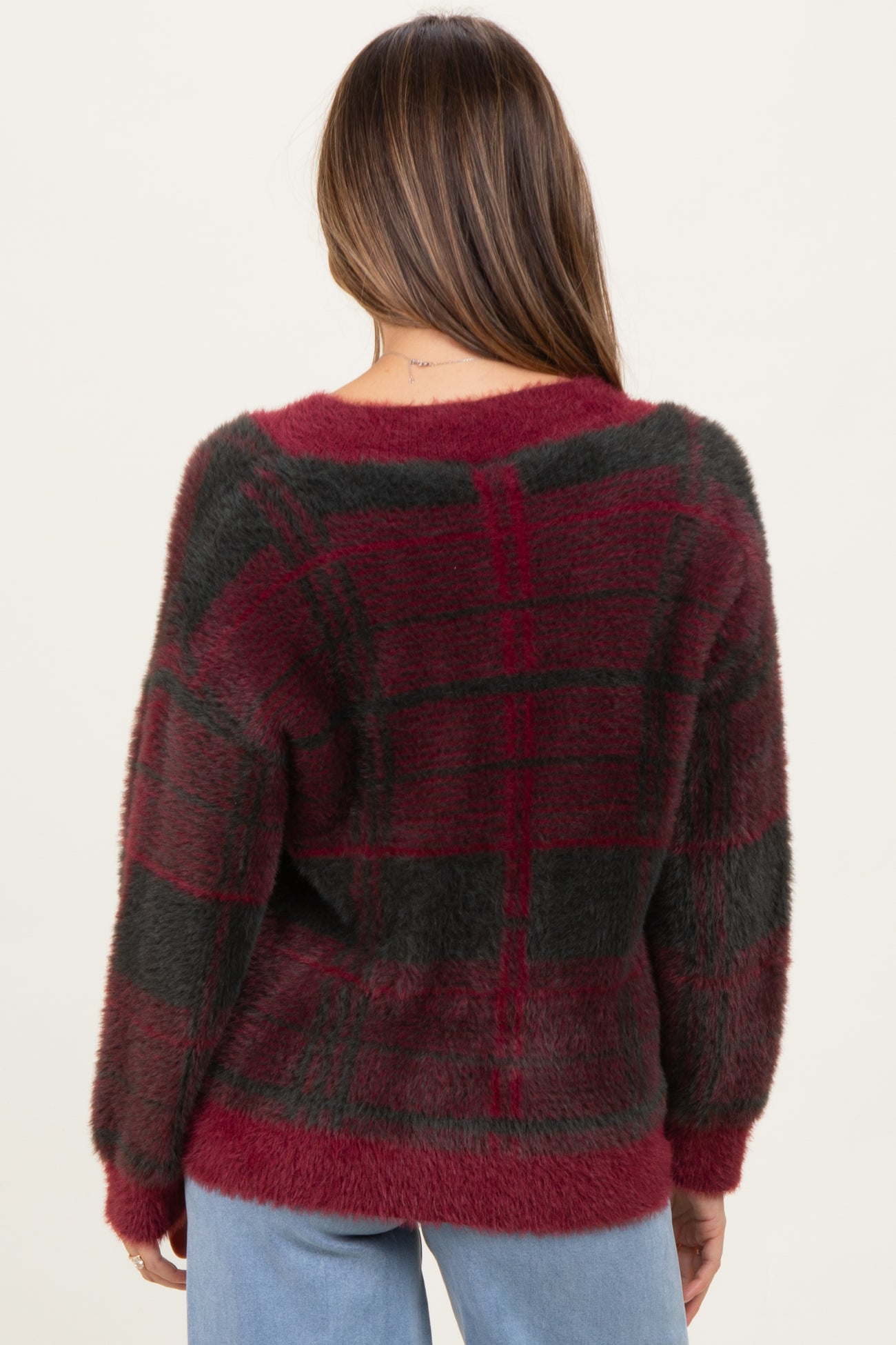 woman wearing a burgundy and black plaid maternity sweater, seen from the back, with loose fit and soft texture