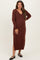 woman wearing a rust-colored long sleeve maternity dress with a v-neck and side slit, showing her baby bump