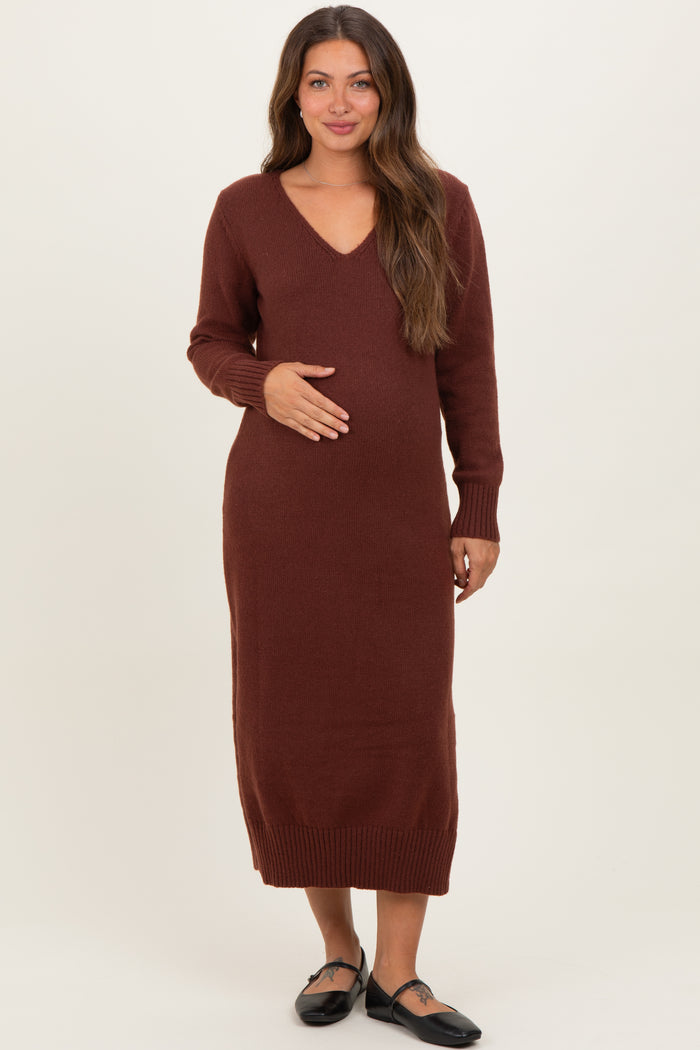 woman wearing a burgundy long sleeve maternity dress with a v-neck and holding her baby bump