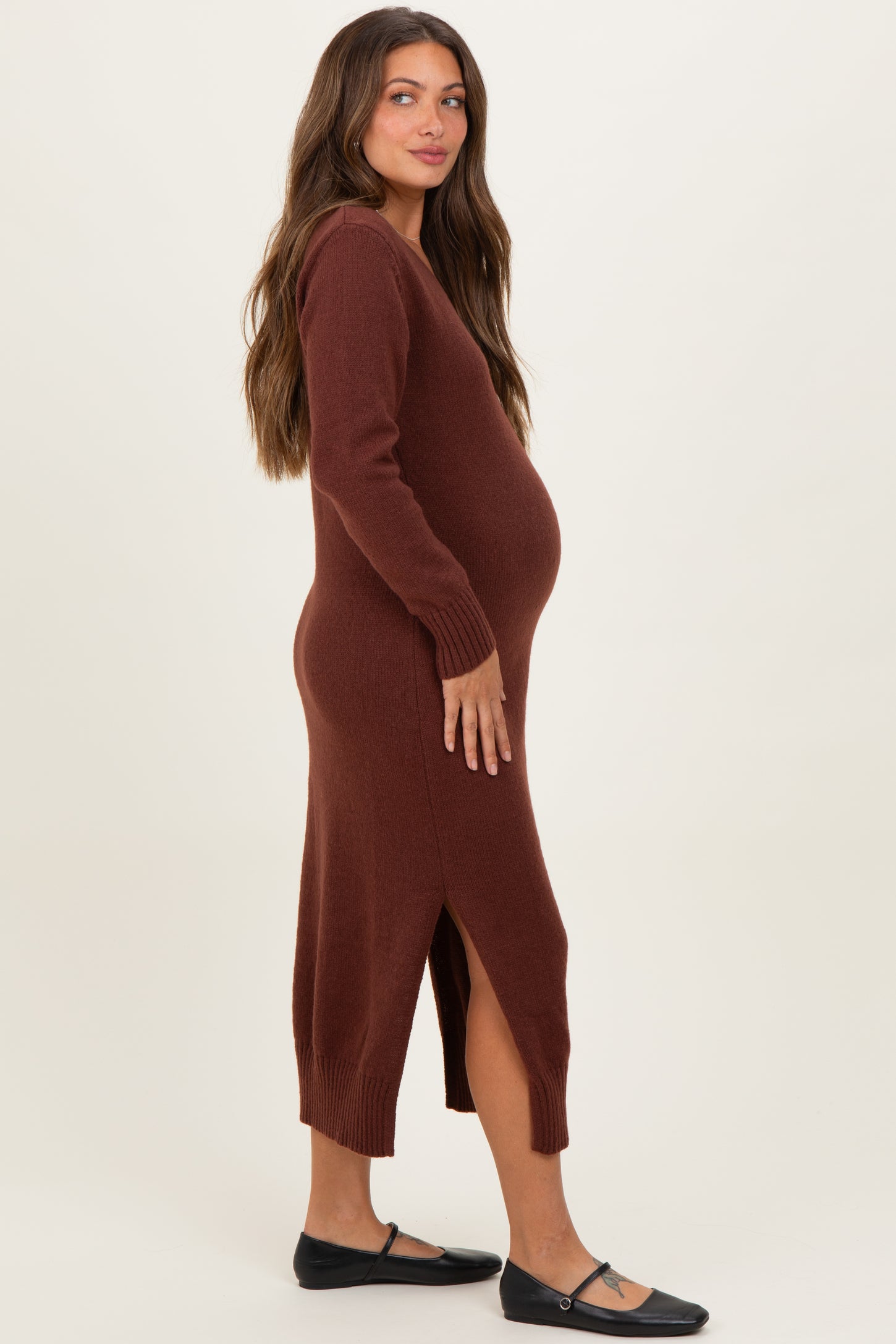 woman wearing a brown long sleeve maternity dress with a side slit and a visible baby bump