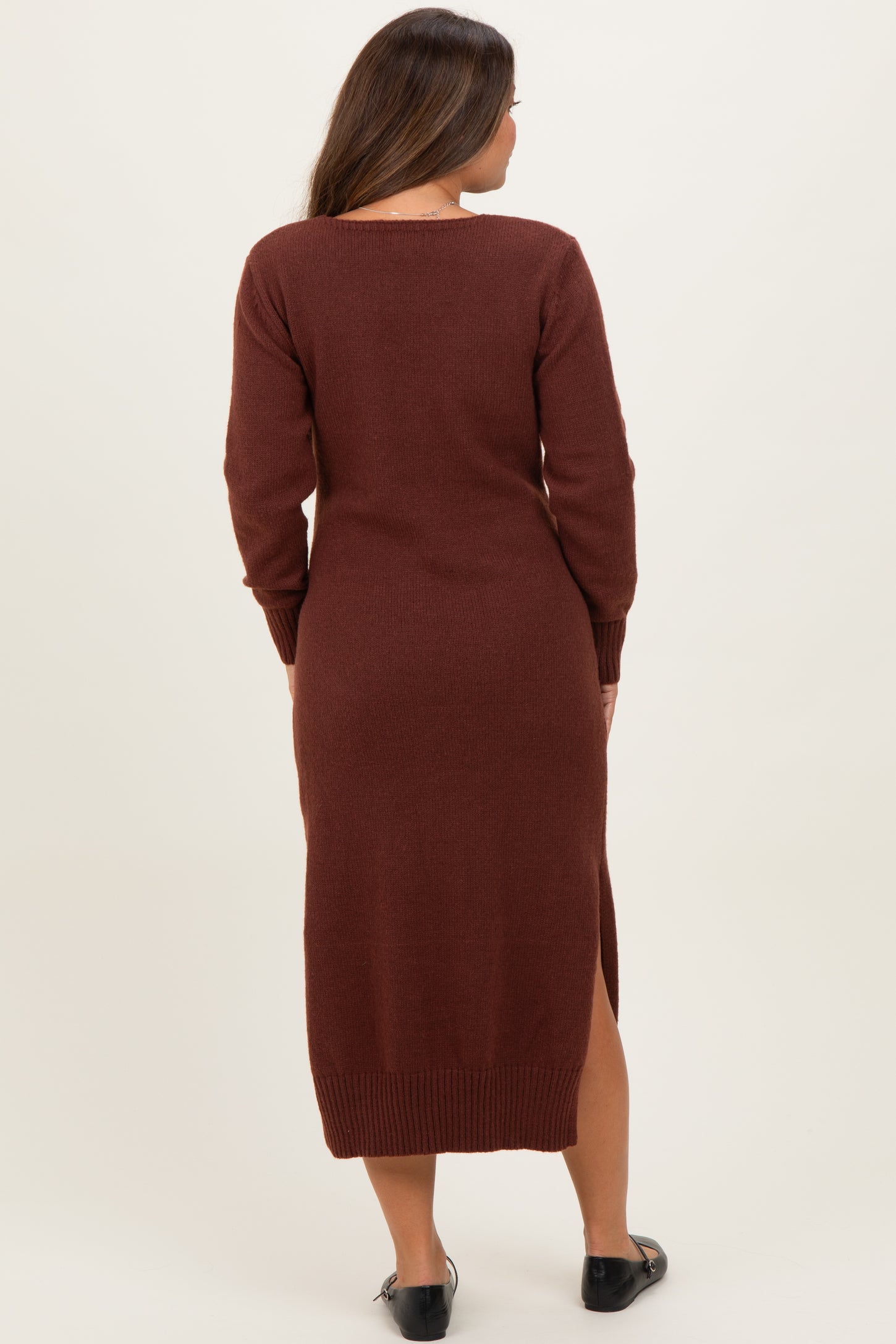 woman wearing a rust long sleeve maternity sweater dress with side slits and a fitted silhouette