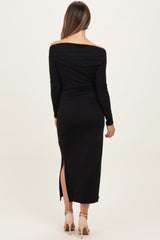 woman wearing a black off-shoulder maternity dress with a side slit, showing her baby bump from the back