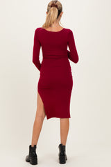 woman wearing a burgundy ribbed maternity dress with long sleeves and a side slit, showing a baby bump
