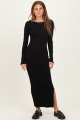 woman wearing a black ribbed long sleeve maxi dress with a side slit and black loafers