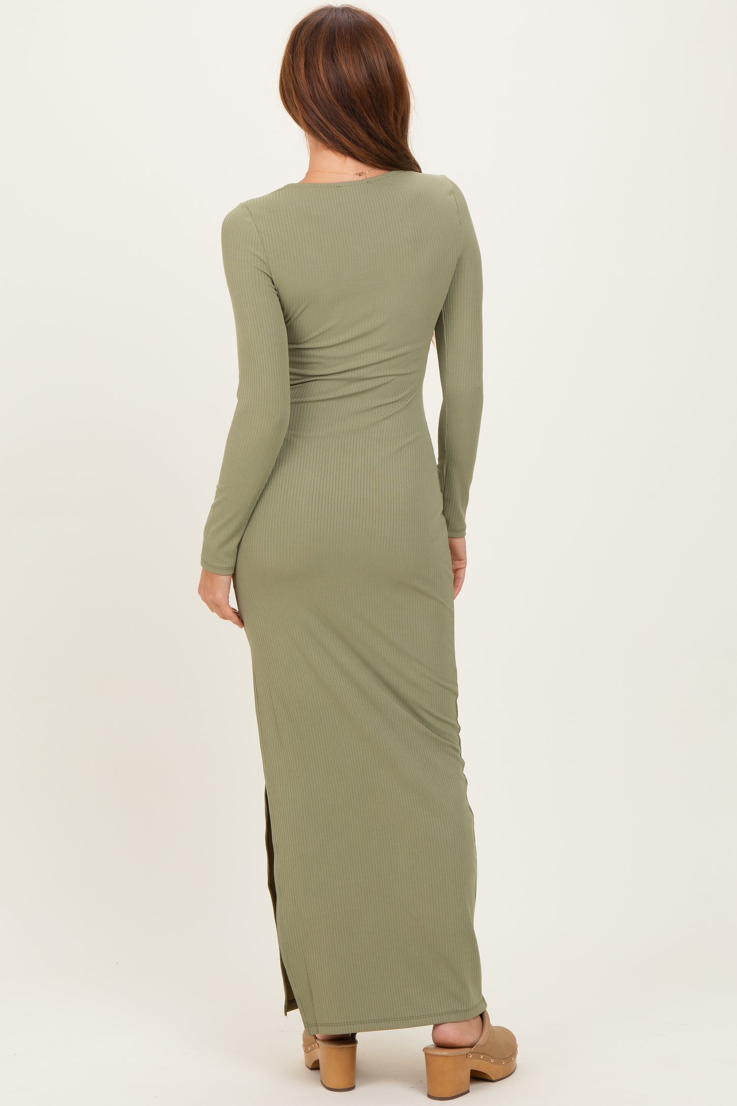 woman wearing a long sleeve olive green ribbed maxi dress with a side slit, shown from the back
