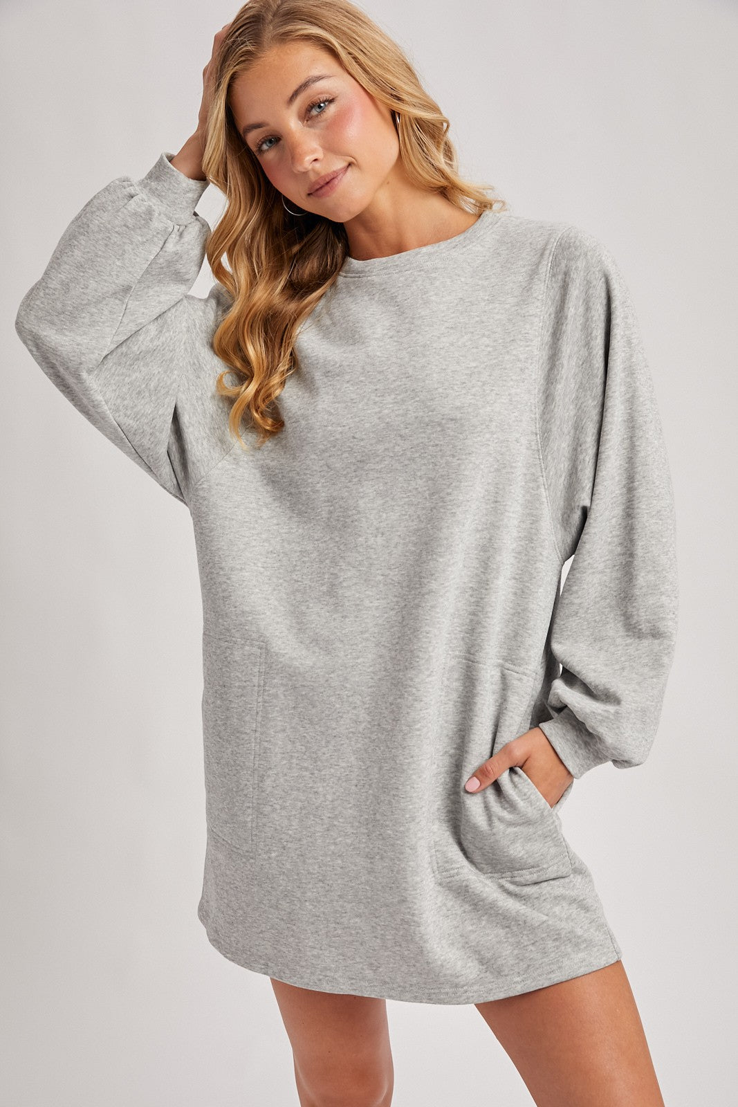 woman wearing a gray oversized sweatshirt dress with long sleeves and side pockets