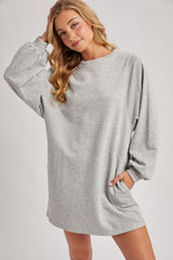 woman wearing a gray oversized sweatshirt dress with long sleeves and side pockets