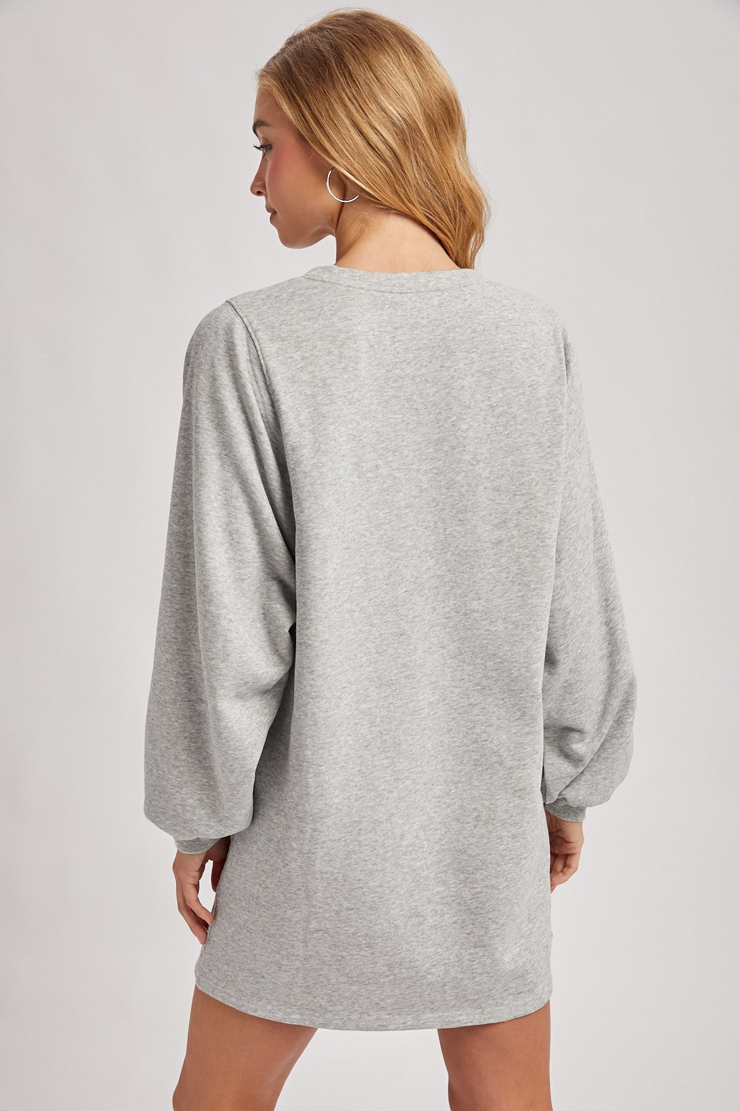woman wearing a gray oversized sweatshirt dress with long puffed sleeves, viewed from the back
