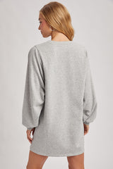 woman wearing a gray oversized sweatshirt dress with long puffed sleeves, viewed from the back