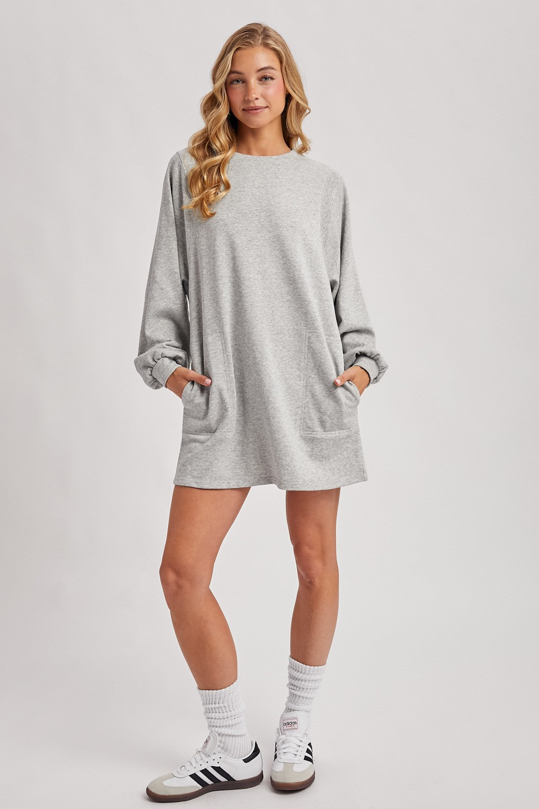 woman wearing a grey oversized sweatshirt dress with pockets and long sleeves