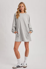 woman wearing a grey oversized sweatshirt dress with pockets and long sleeves