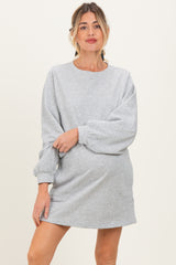 woman wearing a gray maternity sweatshirt dress with balloon sleeves and a visible baby bump