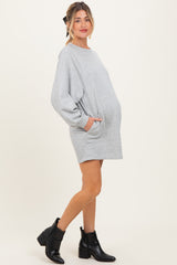 woman wearing a gray maternity sweater dress with pockets and long sleeves, emphasizing her baby bump