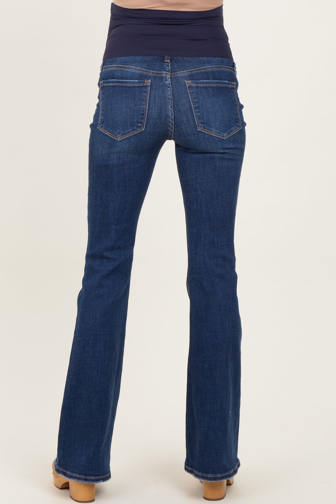 woman wearing dark blue maternity jeans with a wide band at the waist, viewed from the back