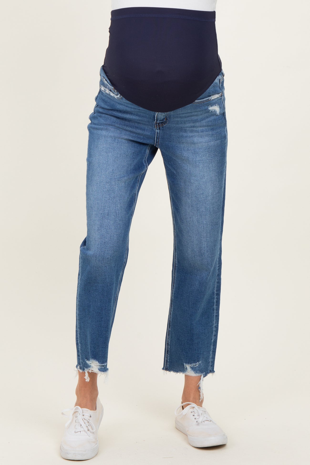 maternity wear distressed blue jeans with a navy over-the-bump band, styled with white sneakers