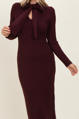 woman wearing a burgundy ribbed knit maxi dress with a bow tie neckline and long sleeves
