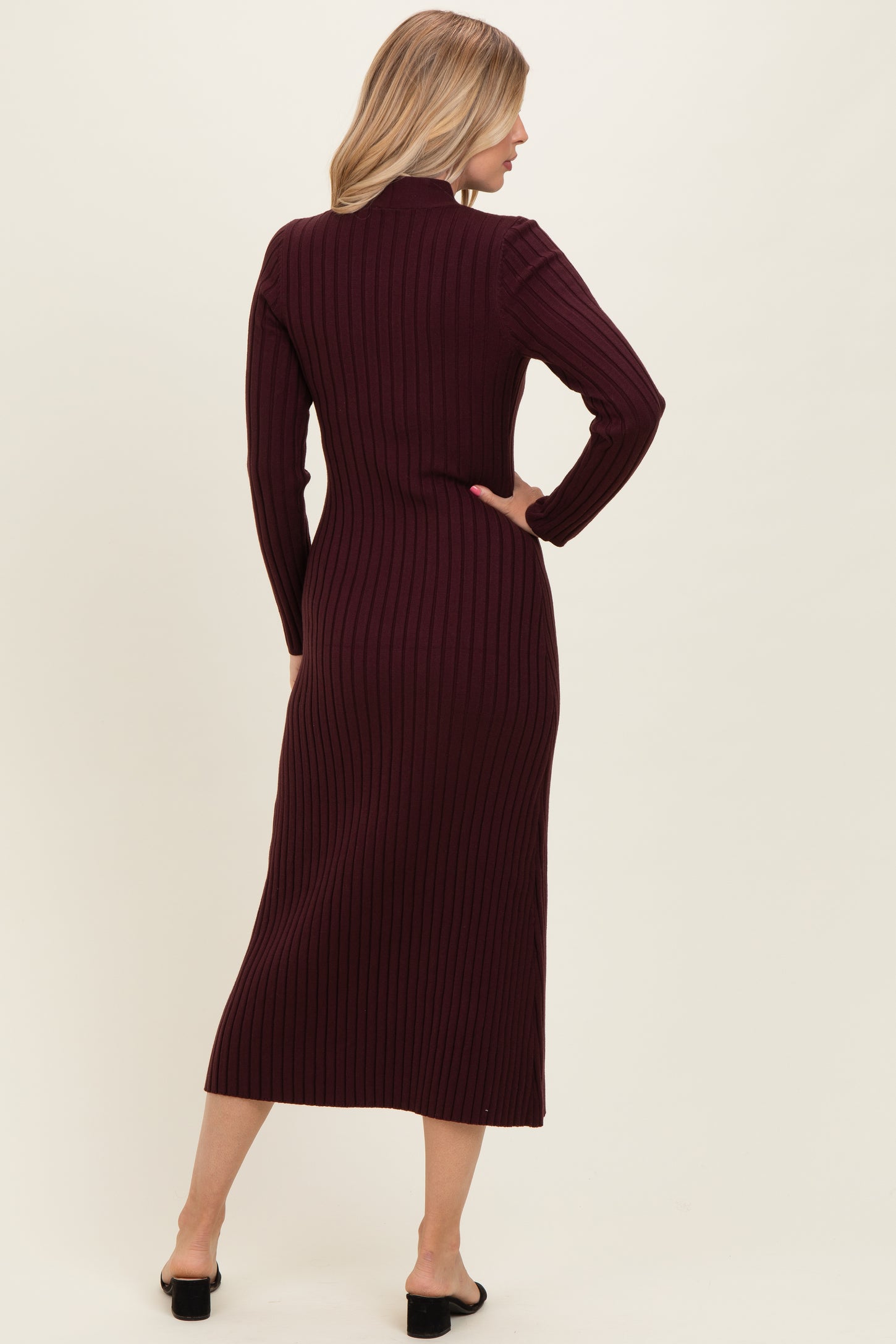 woman wearing a burgundy ribbed midi dress with long sleeves and a fitted silhouette, seen from the back