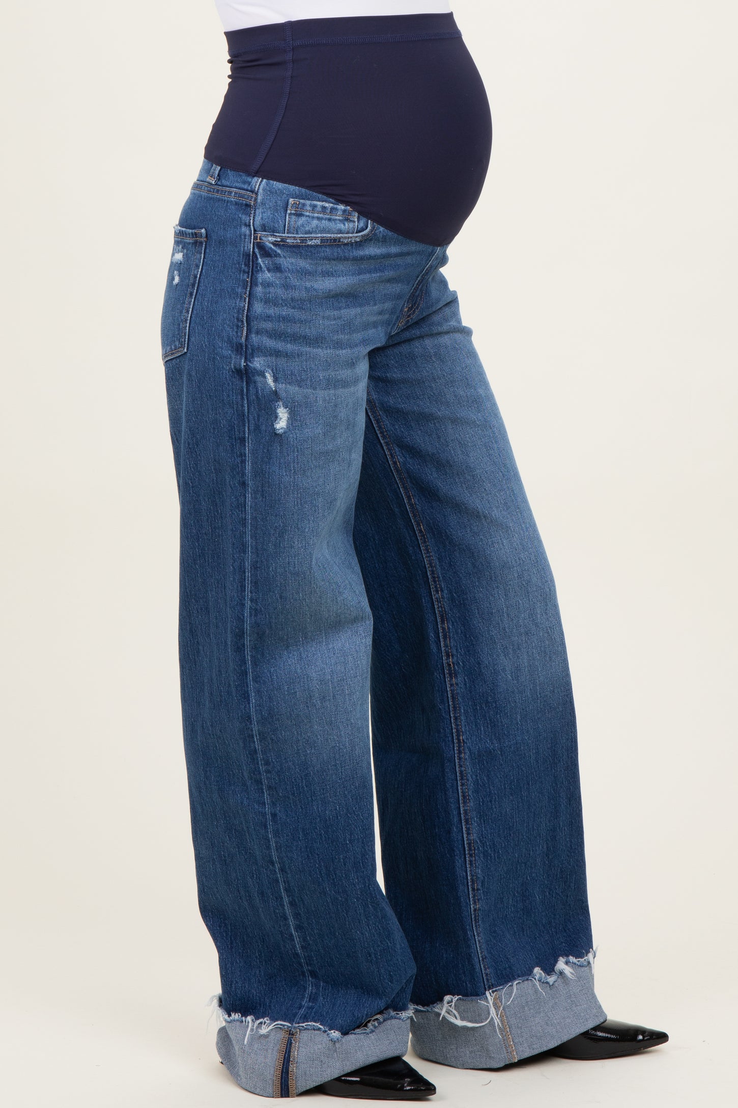 woman wearing distressed wide-leg maternity jeans with a navy blue waistband and a visible baby bump