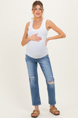 woman wearing a white ribbed maternity tank top and distressed blue maternity jeans, holding her baby bump