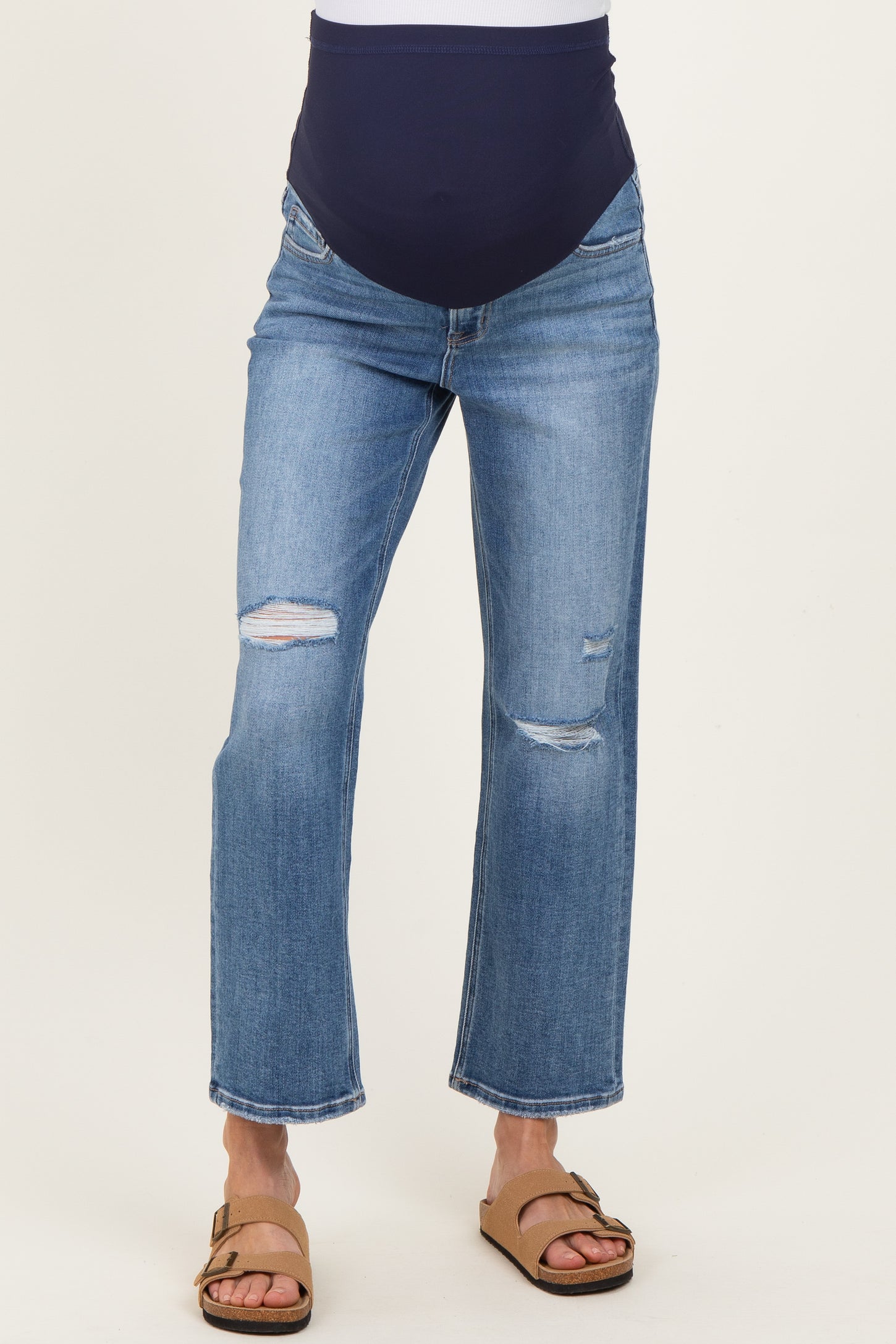 woman wearing blue distressed maternity jeans with a navy belly panel and brown sandals