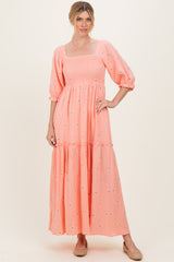 woman wearing a coral tiered maxi dress with puff sleeves and floral embroidery